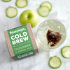 10 pack of apple and cucumber cold brew tea next to a prepared glass of cold brew tea