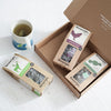 15 pack of everyday brew, 15 pack of peppermint leaves, and 15 pack of mao feng green tea next to a prepared cup of tea